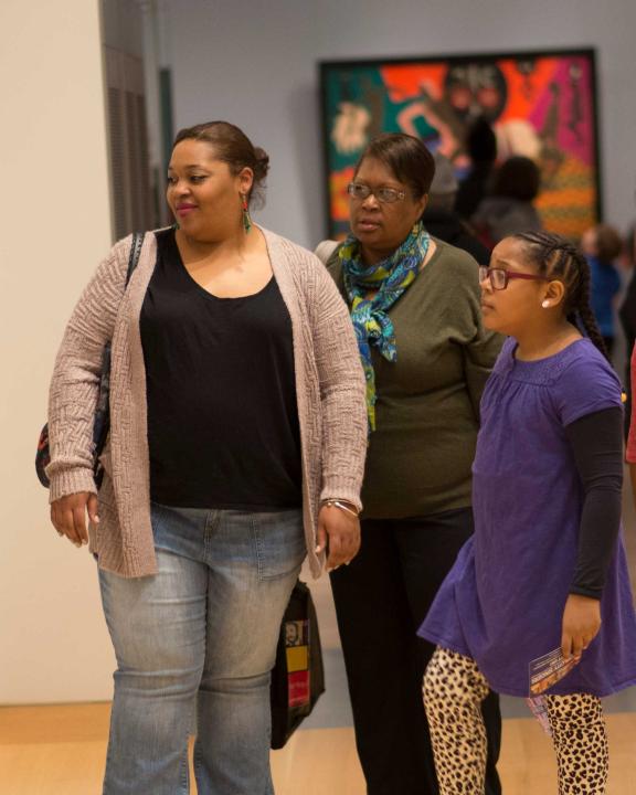 Multigenerational family looking at paintings hanging on gallery wall