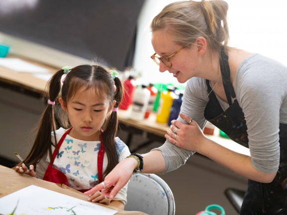 Studio art instructor assisting young female student