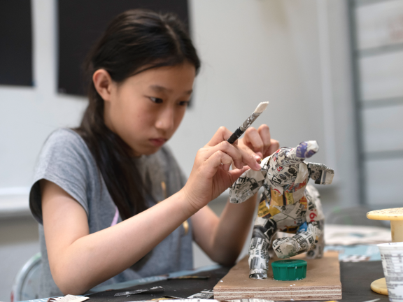 young female student making paper mache sculpture